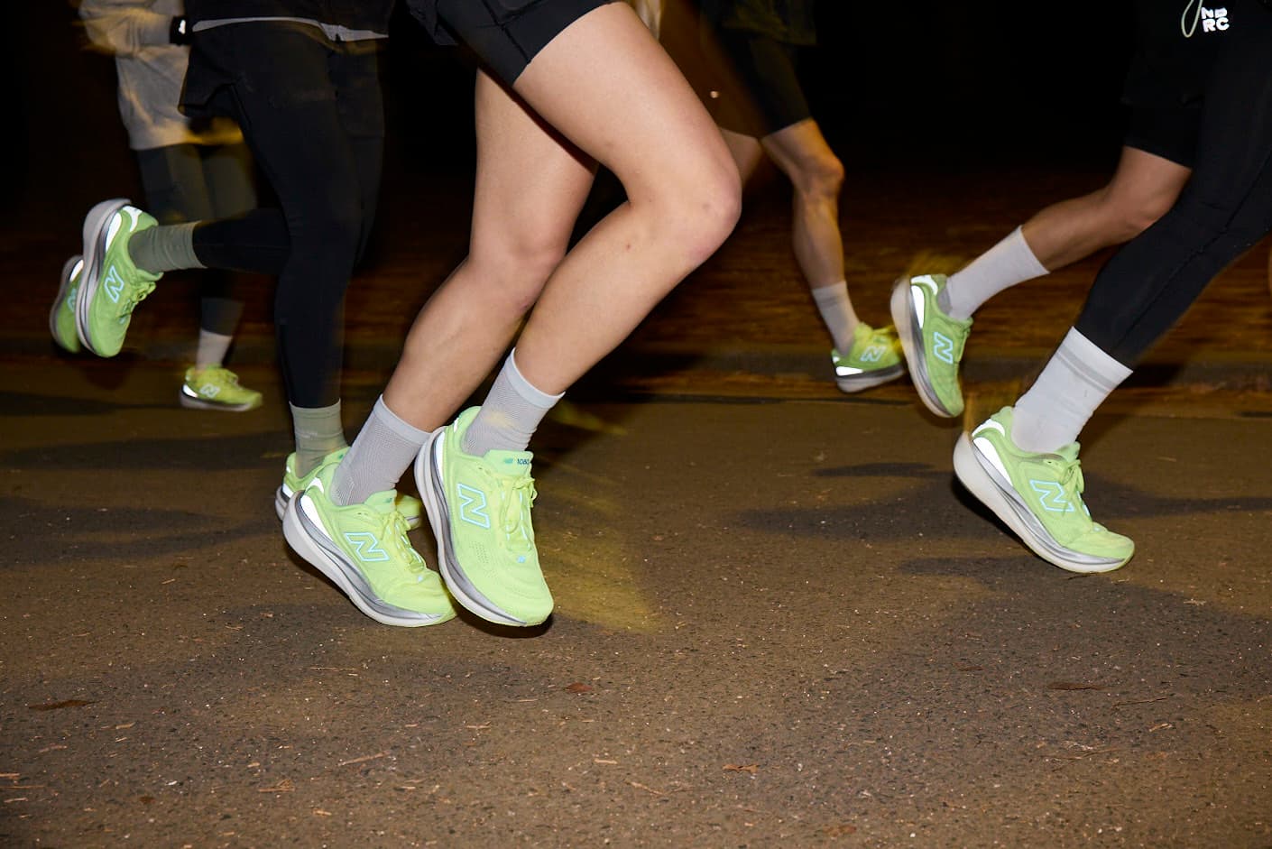 夜の路上を並んで走るランナーたちの足元
